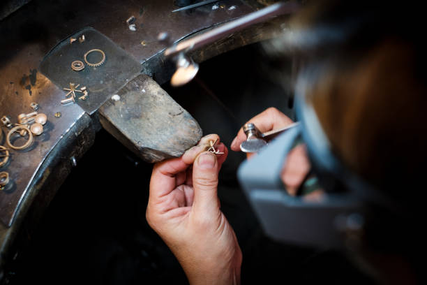 Jeweler saws with small saw at a gold ring in an authentic jewellery workshop
